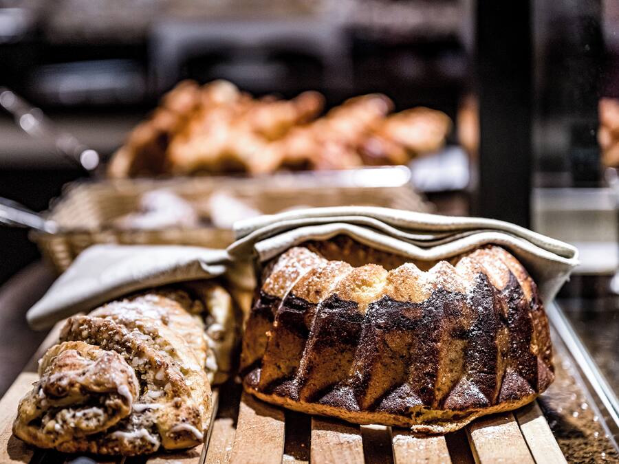 Verschiedene Backwaren auf Holztabletts, darunter ein Brot und Gebäck.