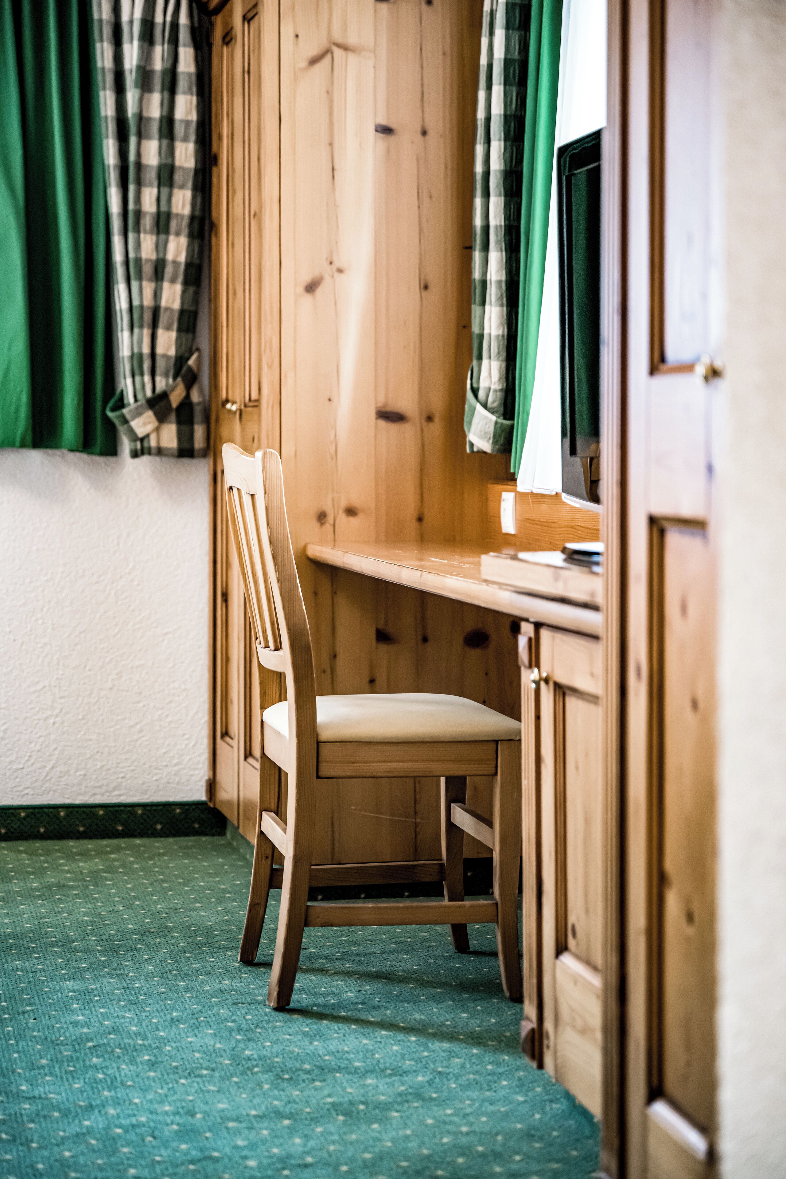 Een houten bureau met een stoel in een kamer met houten wanden en een groen tapijt.