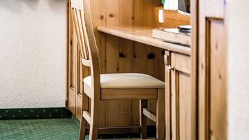Ein Holztisch mit Stuhl in einem Raum mit Holzwänden und einem grünen Teppich.