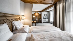 Hotellihuone, jossa on kaksi sänkyä, puinen katto, työpöytä tuolilla ja näkymä ulos.