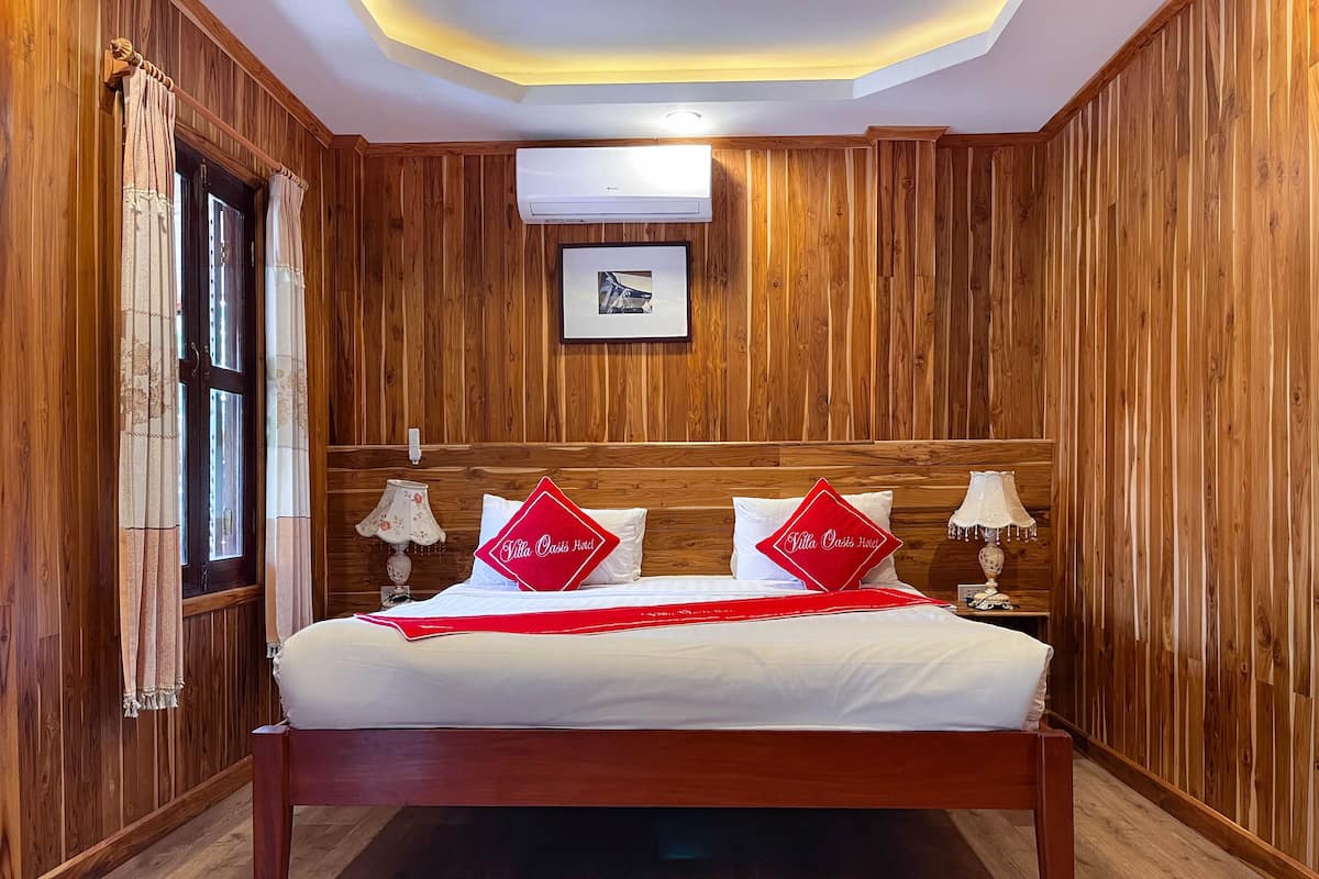 A neatly made bed with two pillows, a bedside lamp, and a framed picture on the wall.