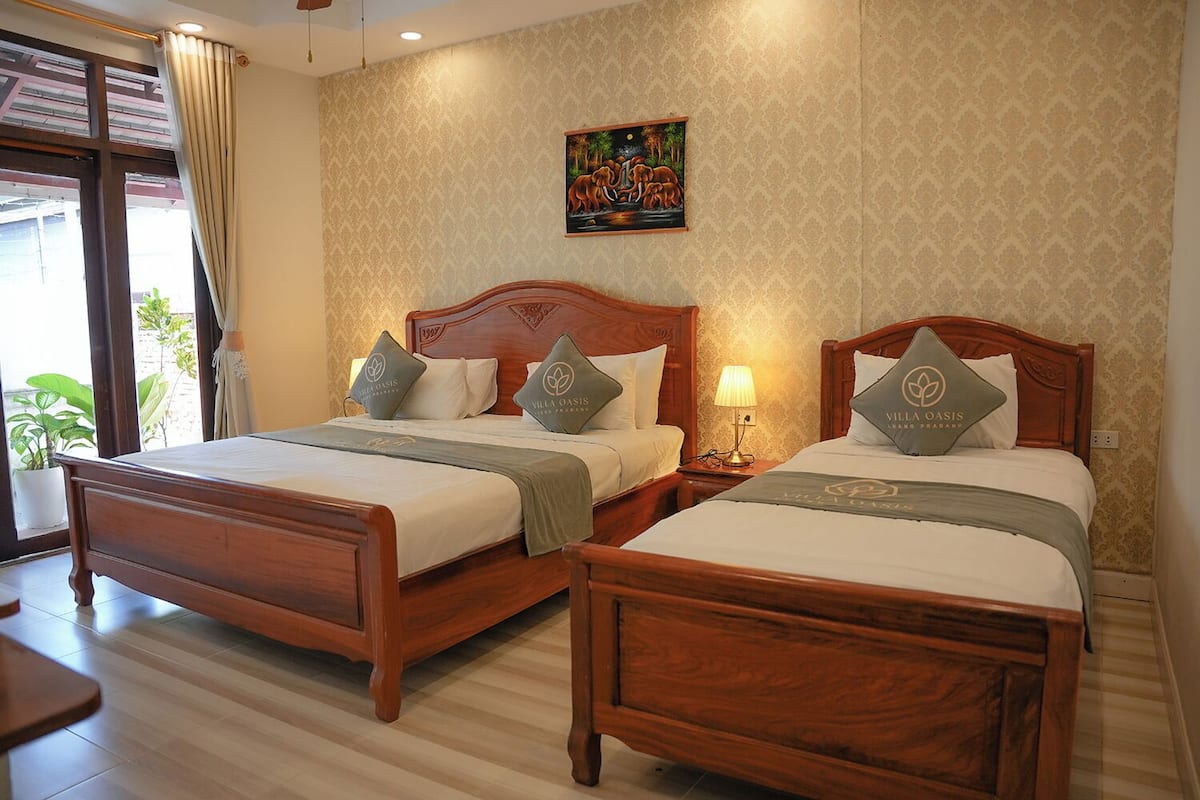 A hotel room with two wooden beds, each with matching pillows and a bedside lamp.
