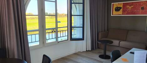 Una habitación con un ventanal grande, un sofá, una mesa de comedor y una silla.