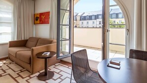 A room with a sofa, a small table, a wicker chair, and a large glass door leading to an outdoor area.