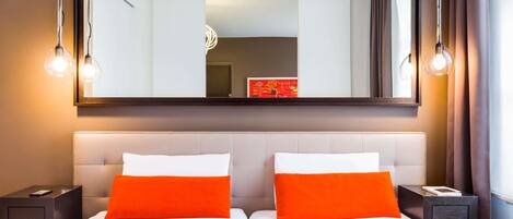 A hotel room with two beds, a large mirror, and bedside lamps.