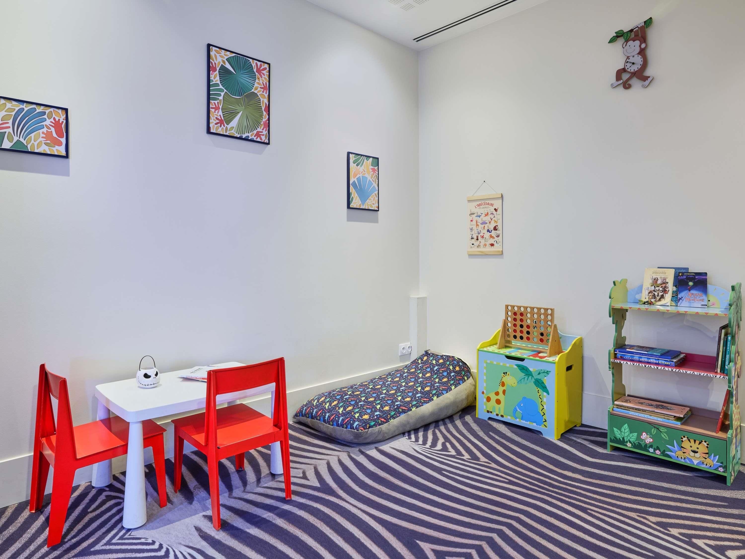Ein Kinderzimmer mit Bett, Schreibtisch, Stühlen, einem Bücherregal und Wanddekorationen.