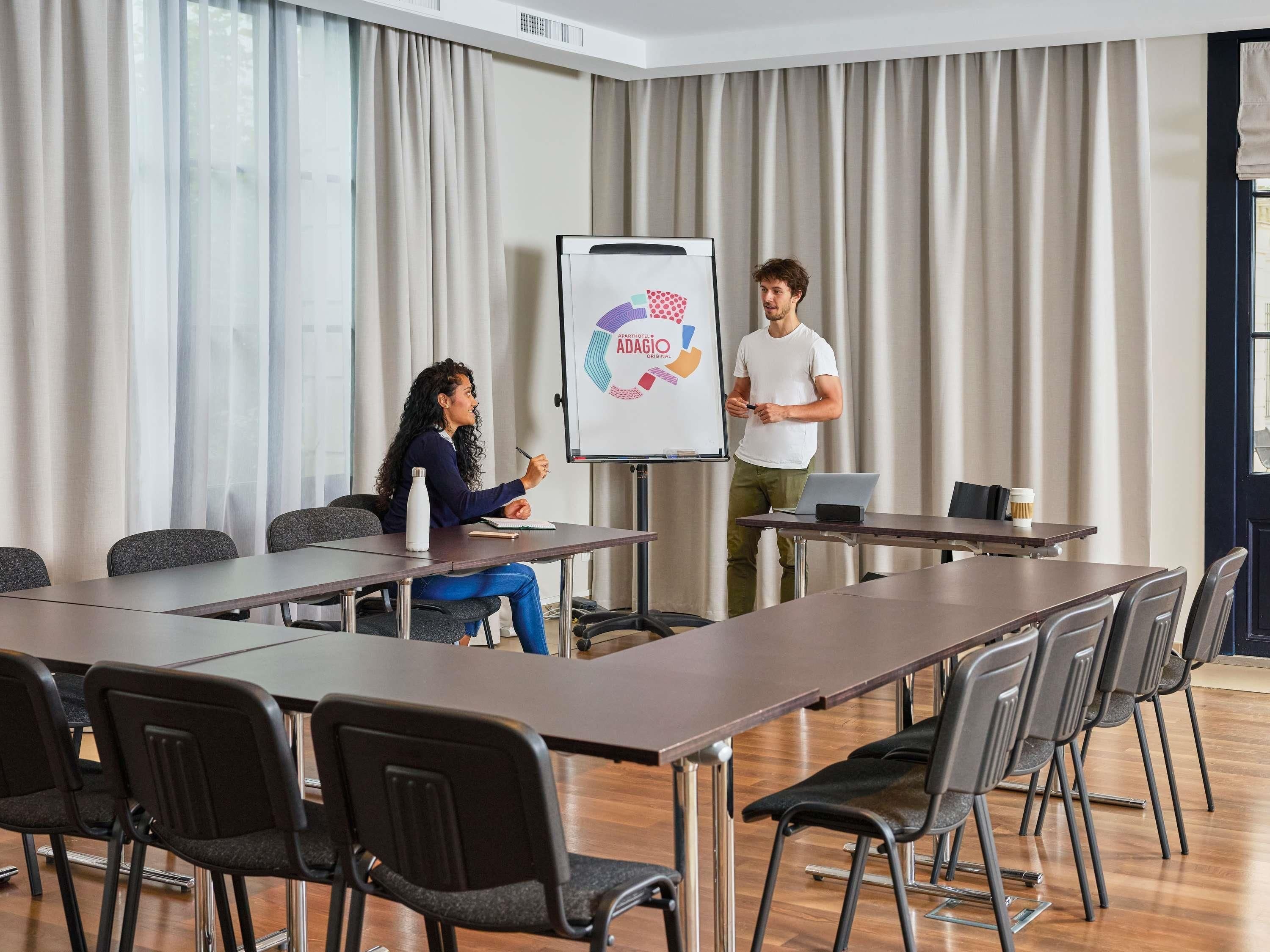 A conference room with a whiteboard, a presentation, and a laptop on a table.
