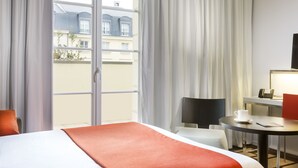 Une chambre d’hôtel avec un lit, une table sur laquelle se trouvent une tasse et une soucoupe, une chaise et un téléviseur.