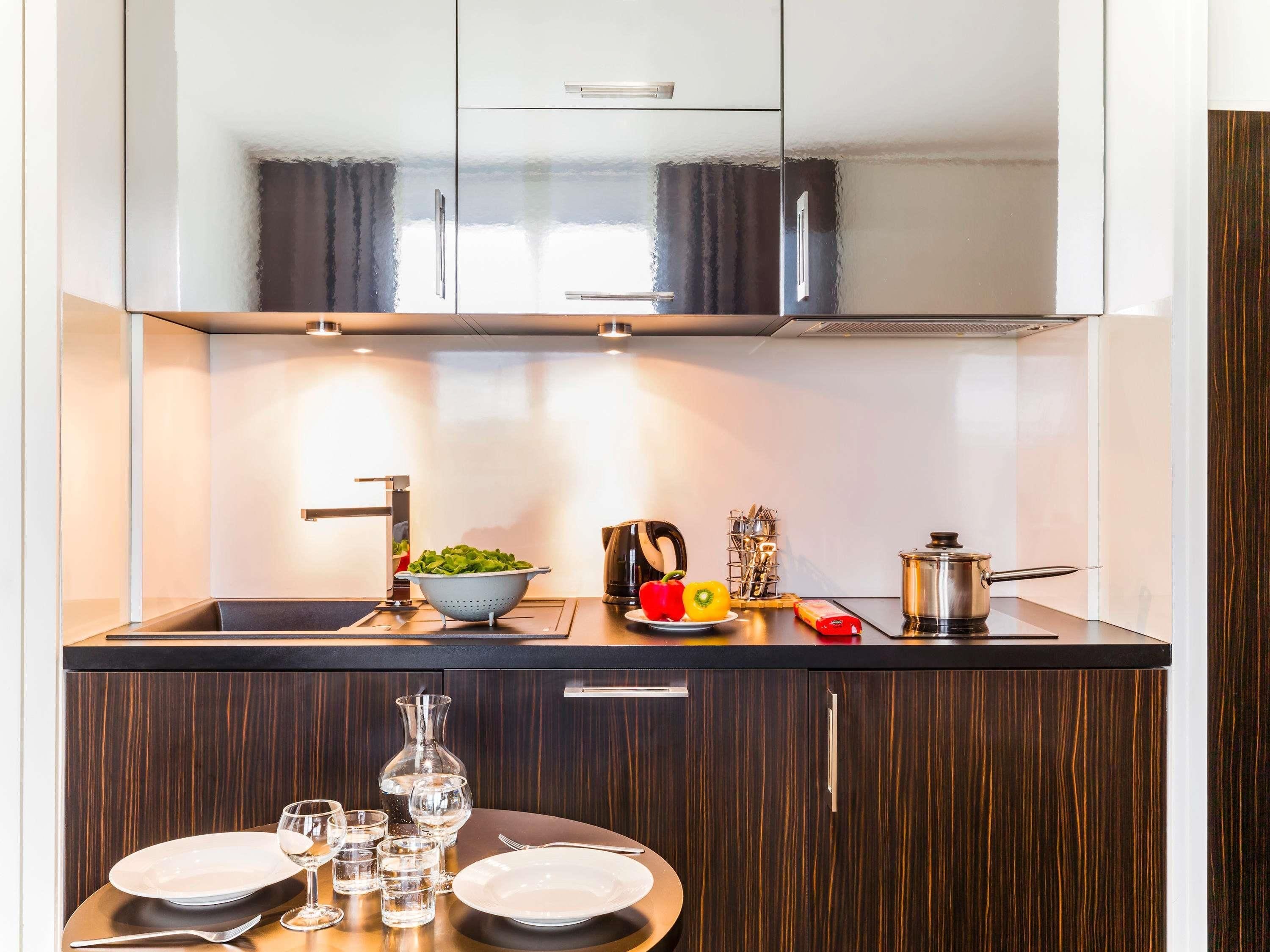 A modern kitchen with a dark wood cabinet, a sink, and a dining area with a table set for two.