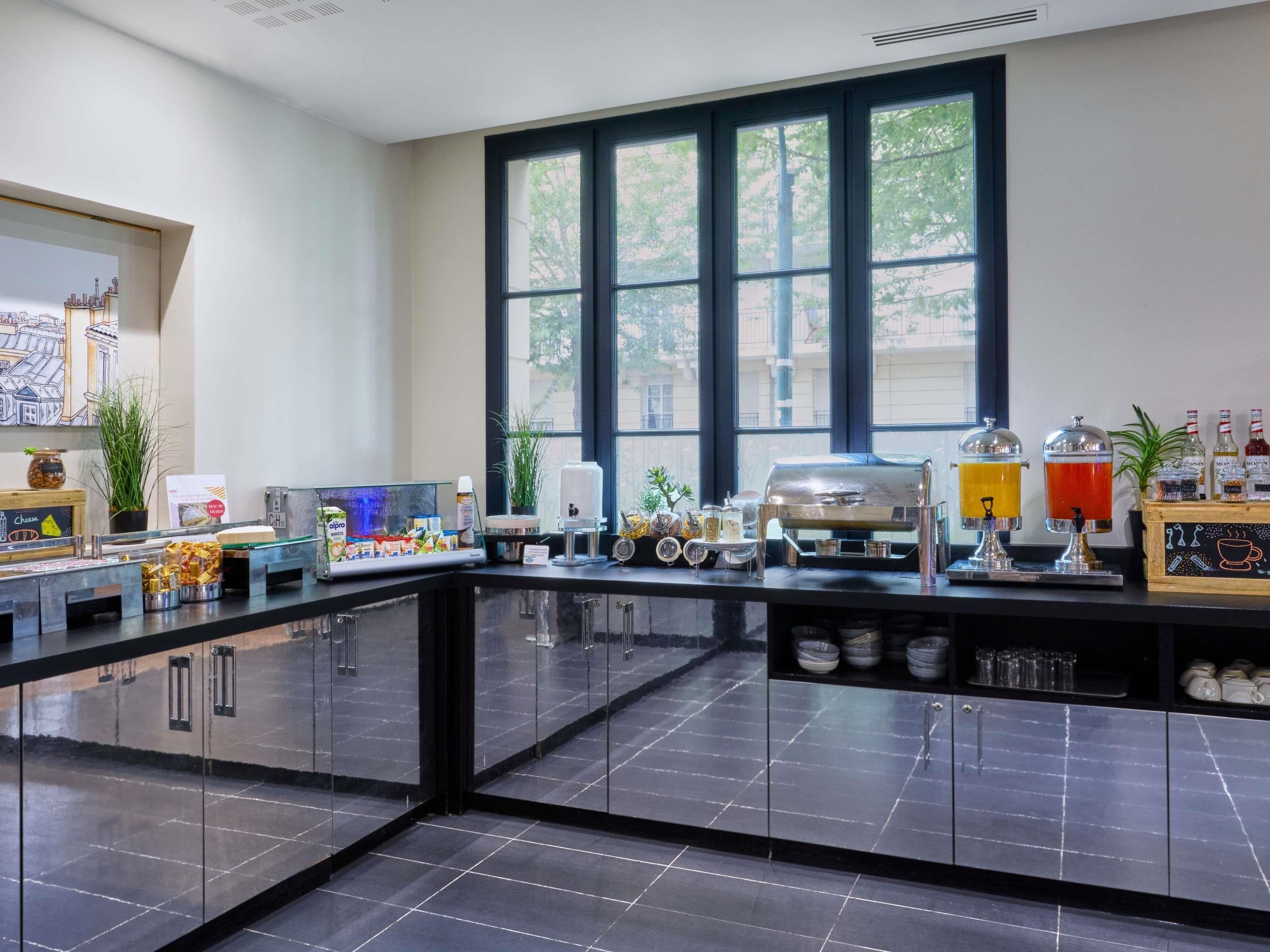 Une cuisine moderne avec une grande fenêtre, une machine à café et divers produits alimentaires disposés sur le plan de travail.