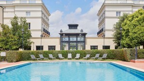 A swimming pool with lounge chairs and a building with a central tower.