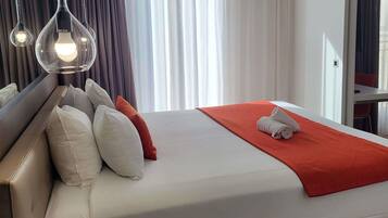 A hotel room with a bed, pillows, a red blanket, and a towel.