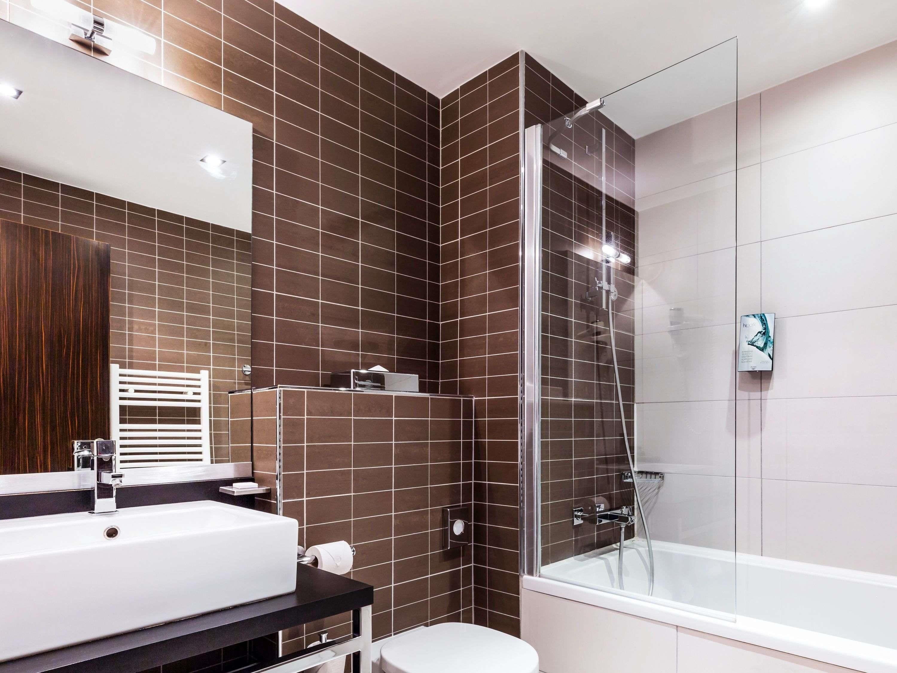 A modern bathroom with a glass-enclosed shower, a white bathtub, and a large sink with a mirror above it.