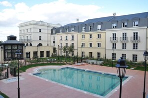 Um pátio de hotel com piscina, um gazebo e uma fileira de edifícios altos.