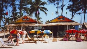 A beachside establishment with two main buildings, each with a sign indicating a place for relaxation. There are several beach chairs and umbrellas under the structures. - A's Holiday Beach Resort (Betalbatim)
