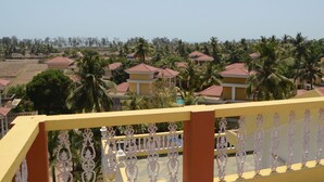 A residential area with houses having red roofs, surrounded by palm trees, and a yellow railing in the foreground. - A's Holiday Beach Resort (Betalbatim)