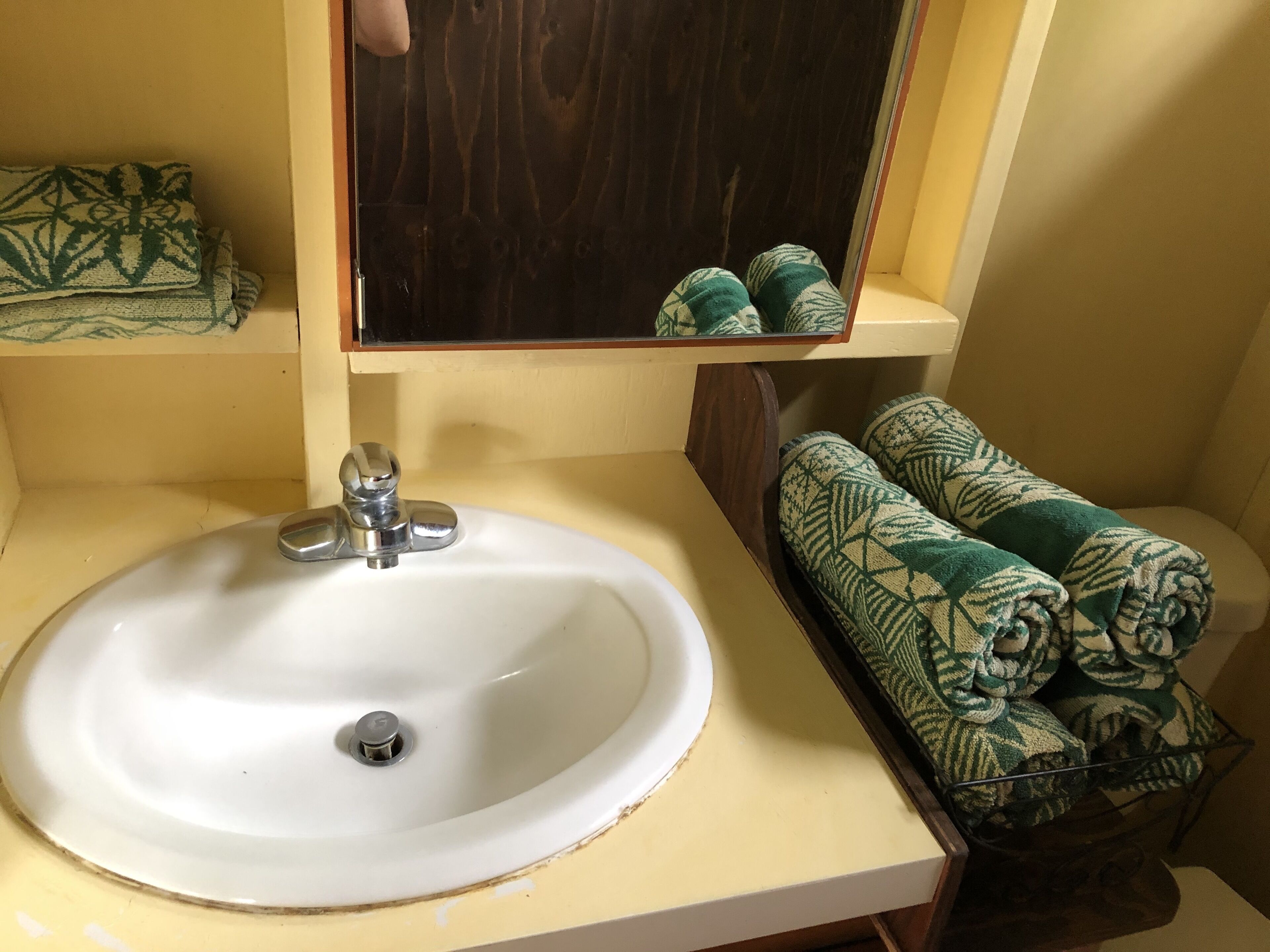 A bathroom with a white sink, a mirror, and a towel rack with green towels.
