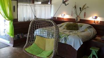 A cozy room with a hanging chair, a bed, a small stool, and a window with curtains.