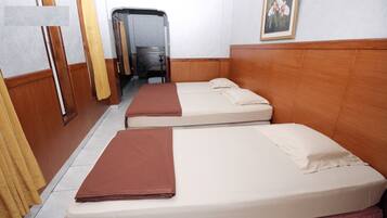 A hotel room with two single beds, wooden headboards, a small bathroom with a shower, and a painting on the wall.