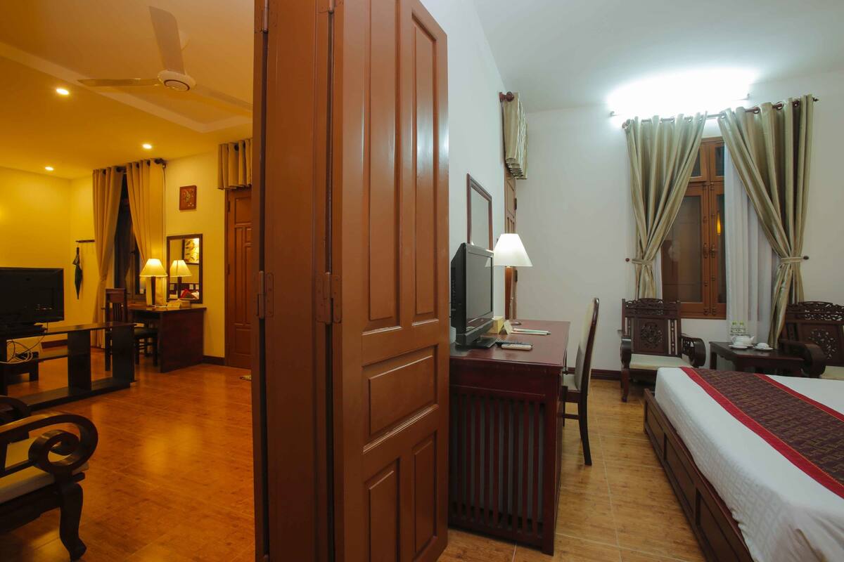 A hotel room with a bed, desk, chair, television, and a ceiling fan.