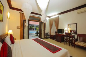 Habitación de hotel con cama, escritorio, silla y vista al exterior.