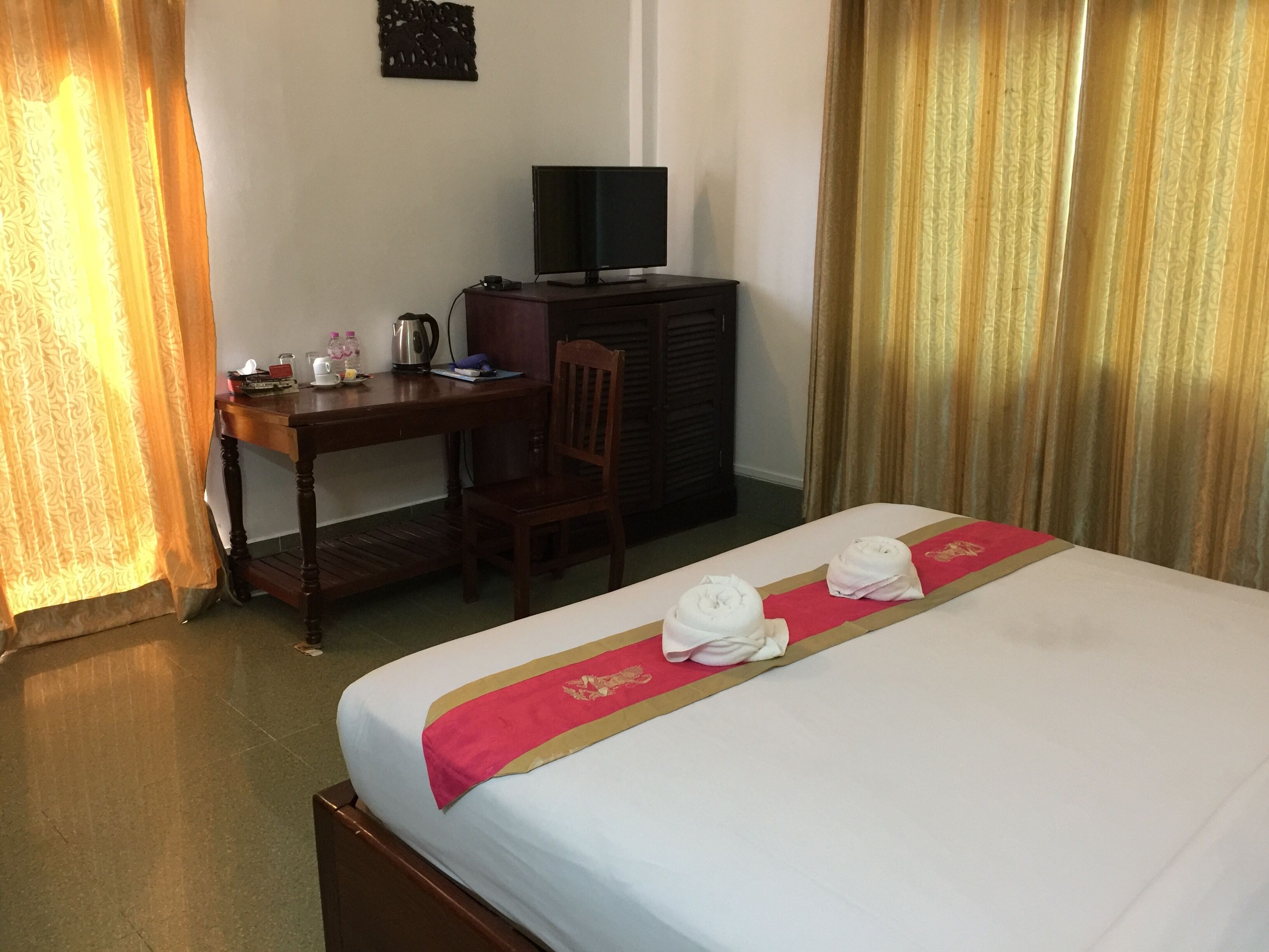 Une chambre d’hôtel avec un lit, un bureau, une télévision et une chaise.