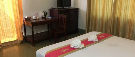 Une chambre d’hôtel avec un lit, un bureau, une télévision et une chaise.