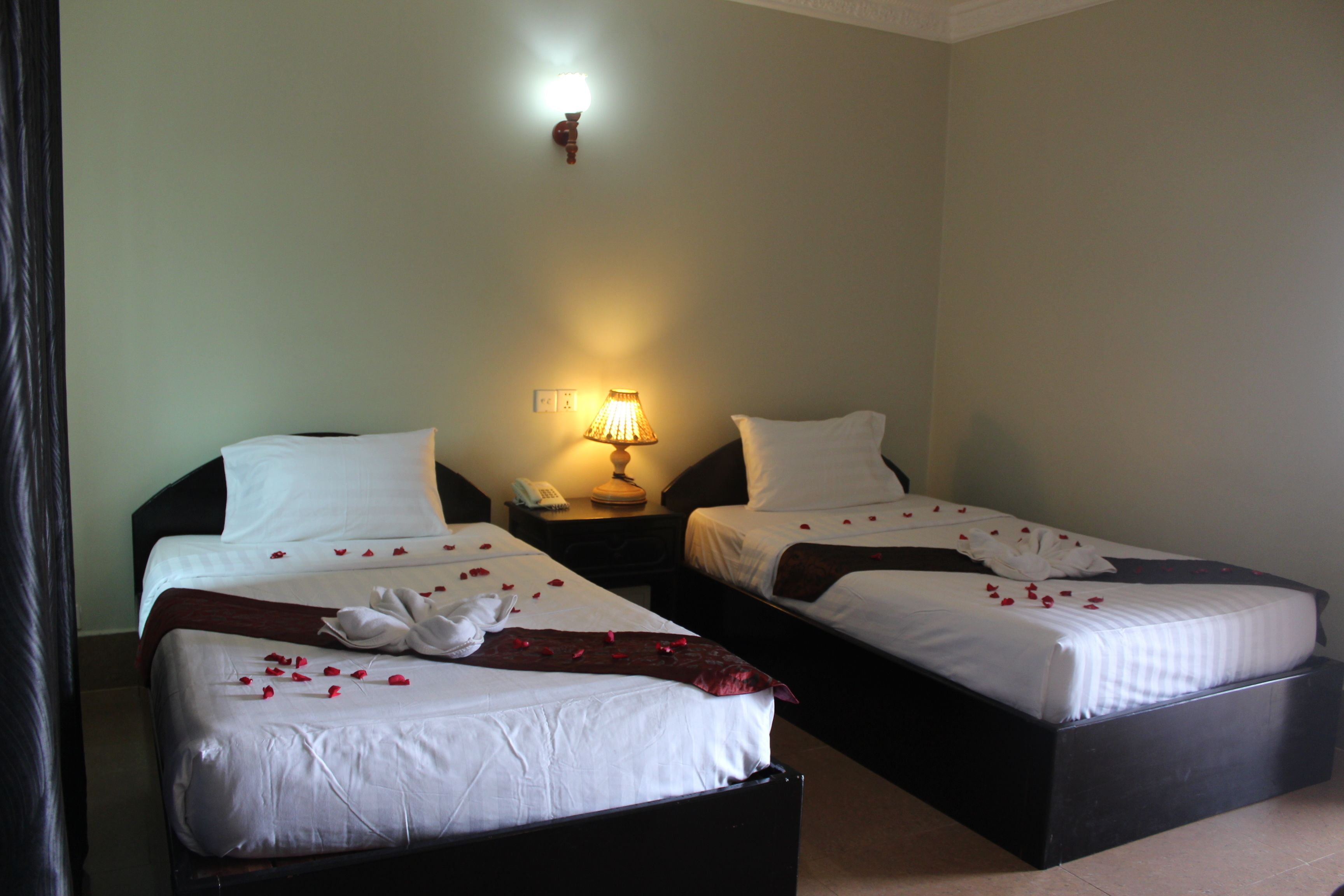 Two single beds with white linens, a bedside lamp, and a telephone on a nightstand.