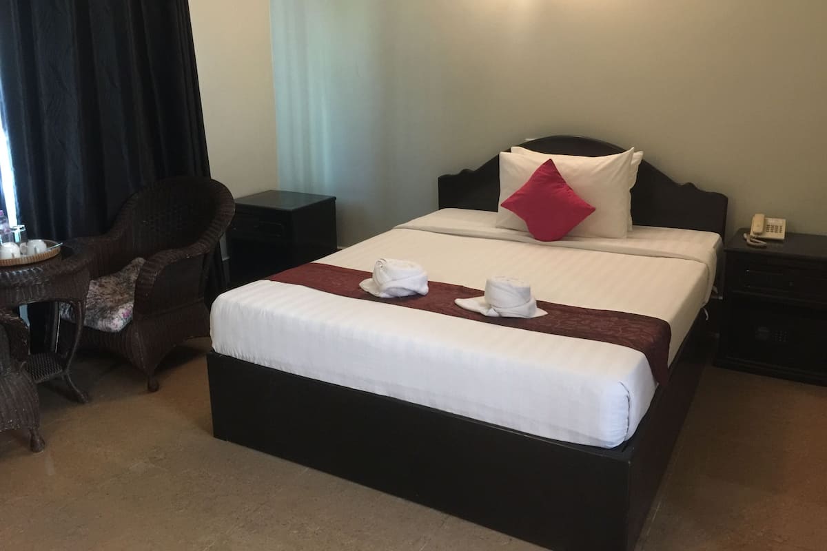 Une chambre d’hôtel avec un lit, une chaise, une table de chevet et une lampe.