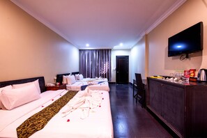 Ein Hotelzimmer mit zwei Betten, einem Fernseher, einem Schreibtisch und einem Kleiderschrank.