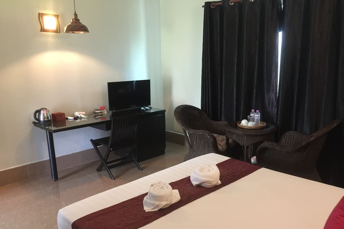 Une chambre d’hôtel comprenant un lit, un bureau avec un ordinateur, une chaise, une petite table avec des bouteilles et un téléviseur.