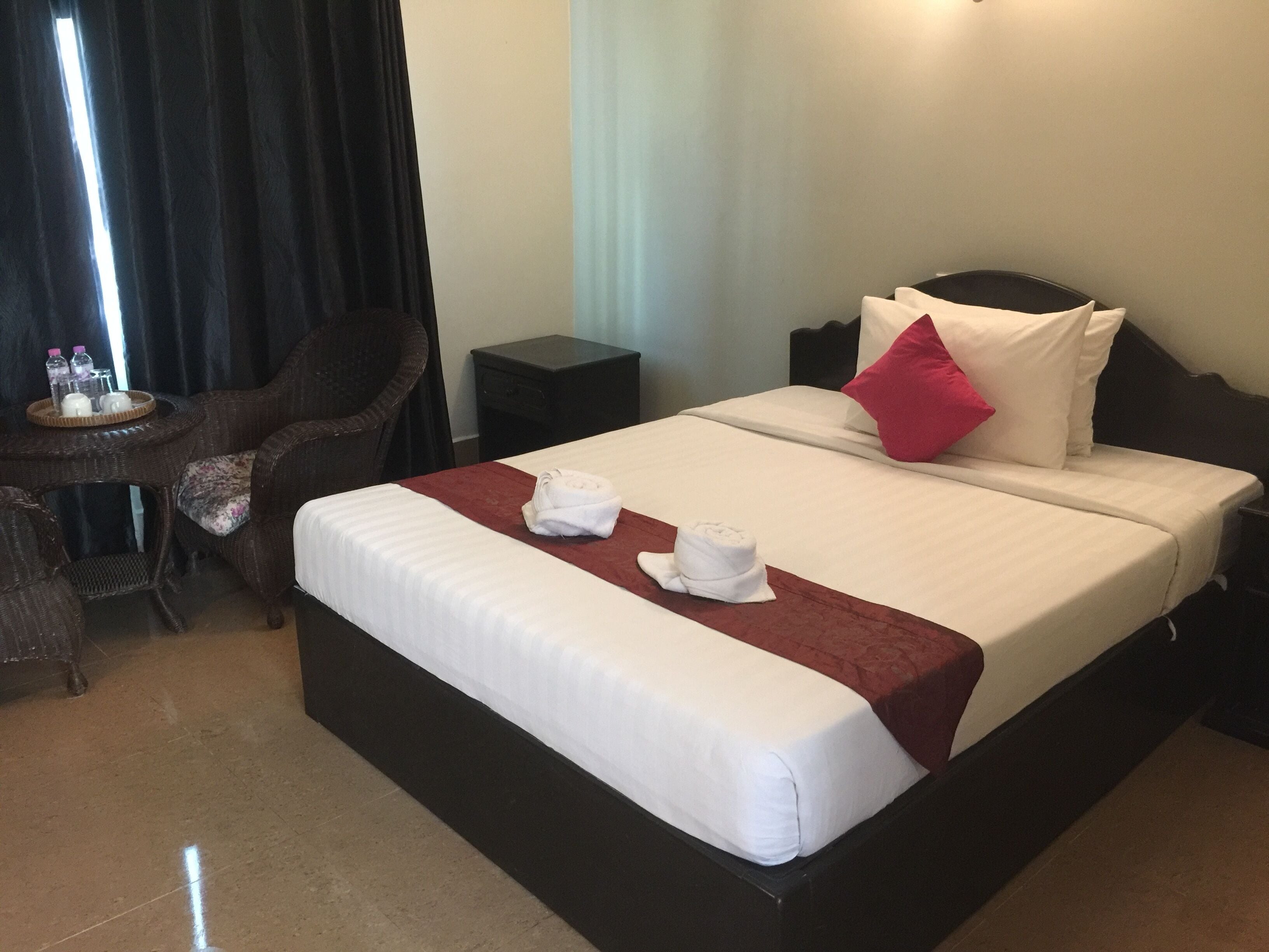 A hotel room with a large bed, a small table with toiletries, a chair, and a nightstand.