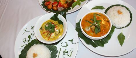 A table with four plates of food, each with rice and a different dish.