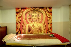 Una habitación con una cama, un gran mural de Buda en la pared y una toalla roja sobre la cama.
