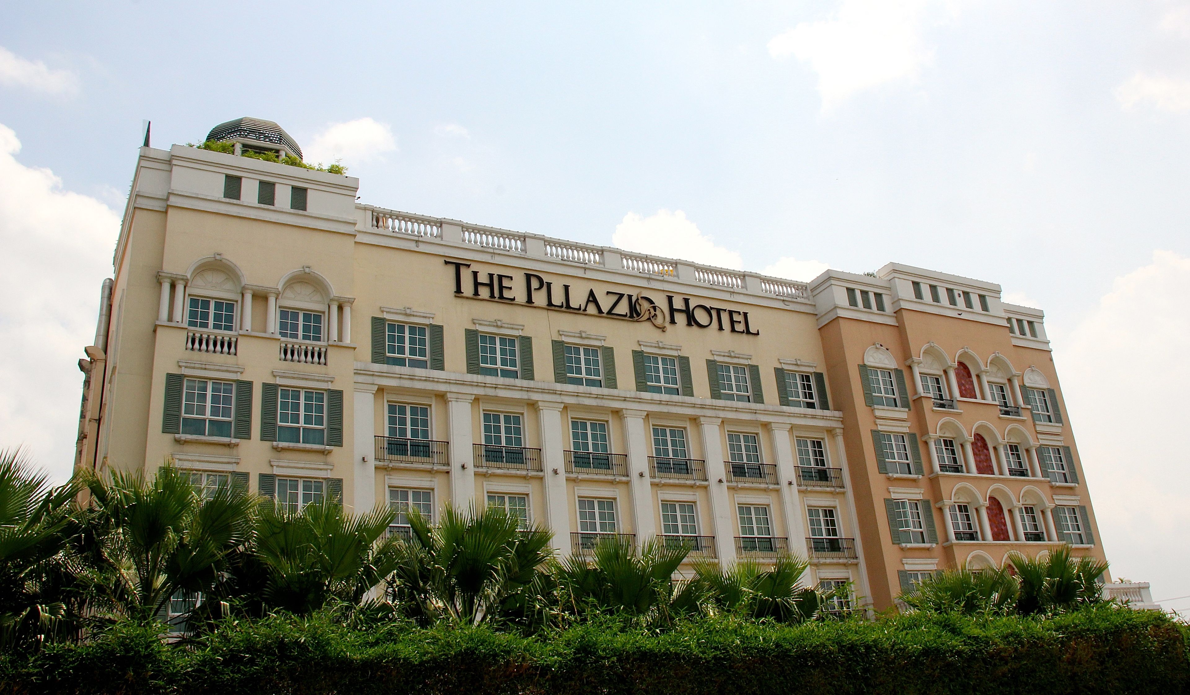 A multi-story hotel with a classic architectural design, featuring balconies and a prominent sign reading "The Plaza Hotel".
