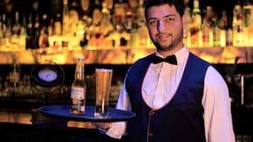 Ein Barkeeper hält ein Tablett mit einer Flasche und einem Glas.