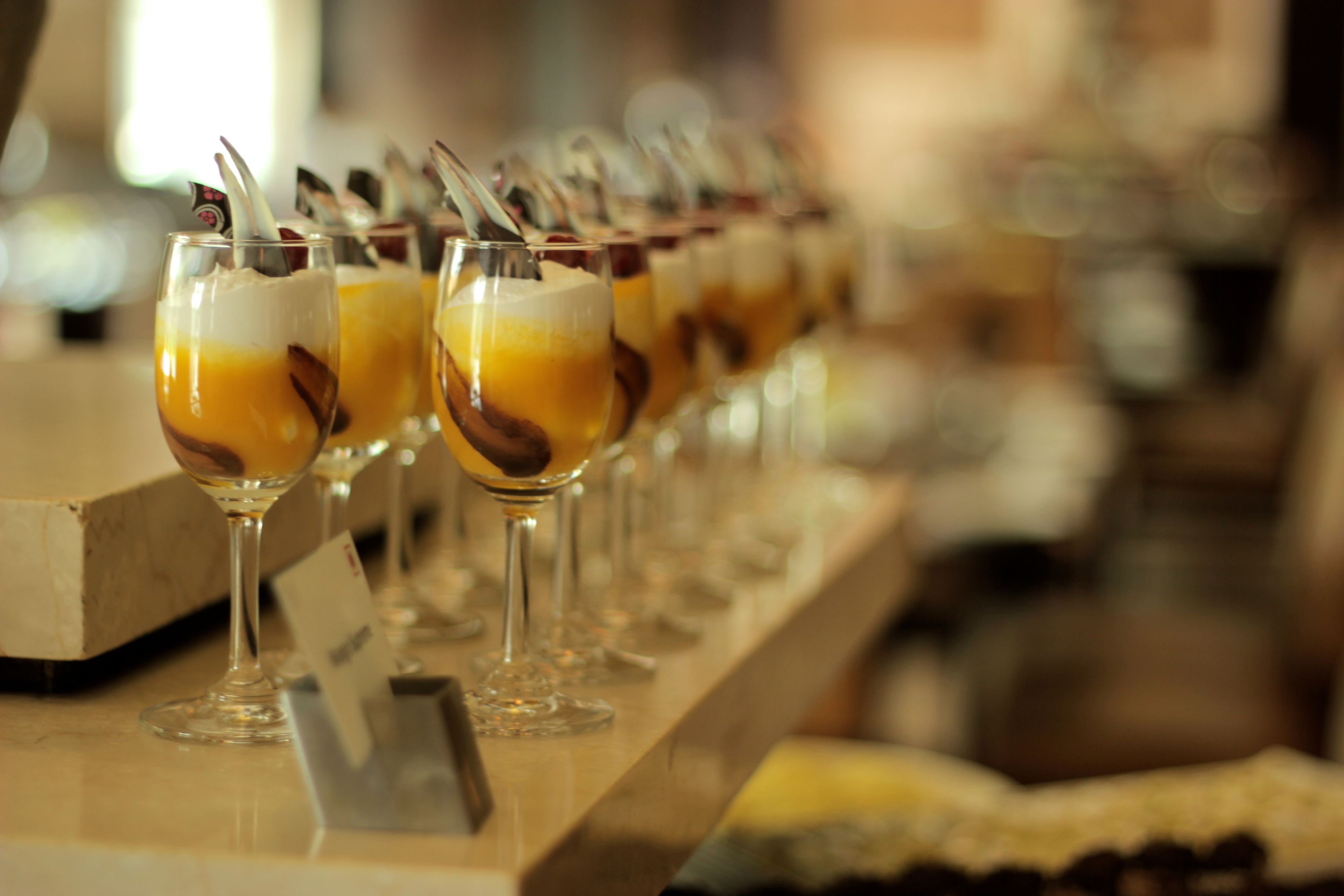 A row of glasses with layered drinks on a bar counter.