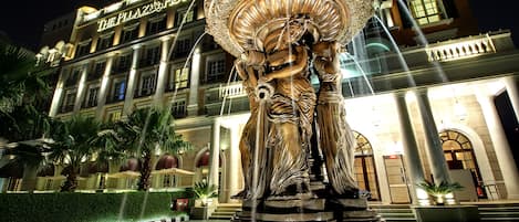 A hotel with a large fountain sculpture in front.