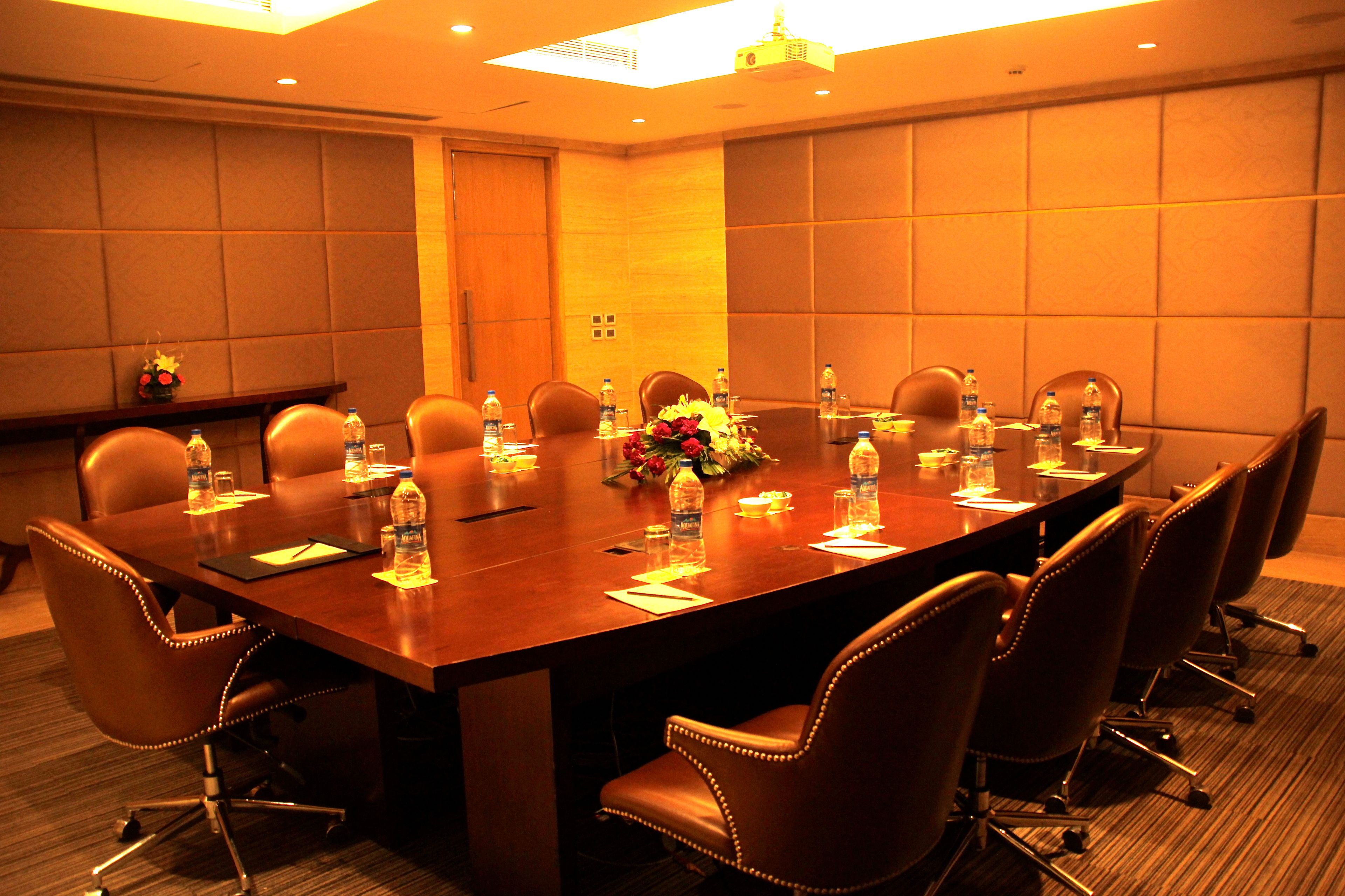 A conference room with a long table, multiple chairs, water bottles, and a floral centerpiece.
