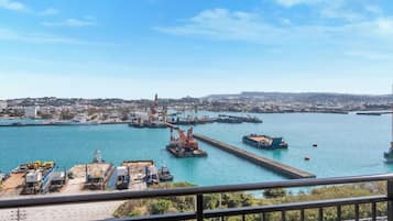 A harbor with ships, cranes, and a cityscape in the background.