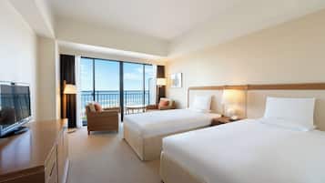 A hotel room with two beds, a desk with a TV, a chair, a lamp, and a view of the sky.