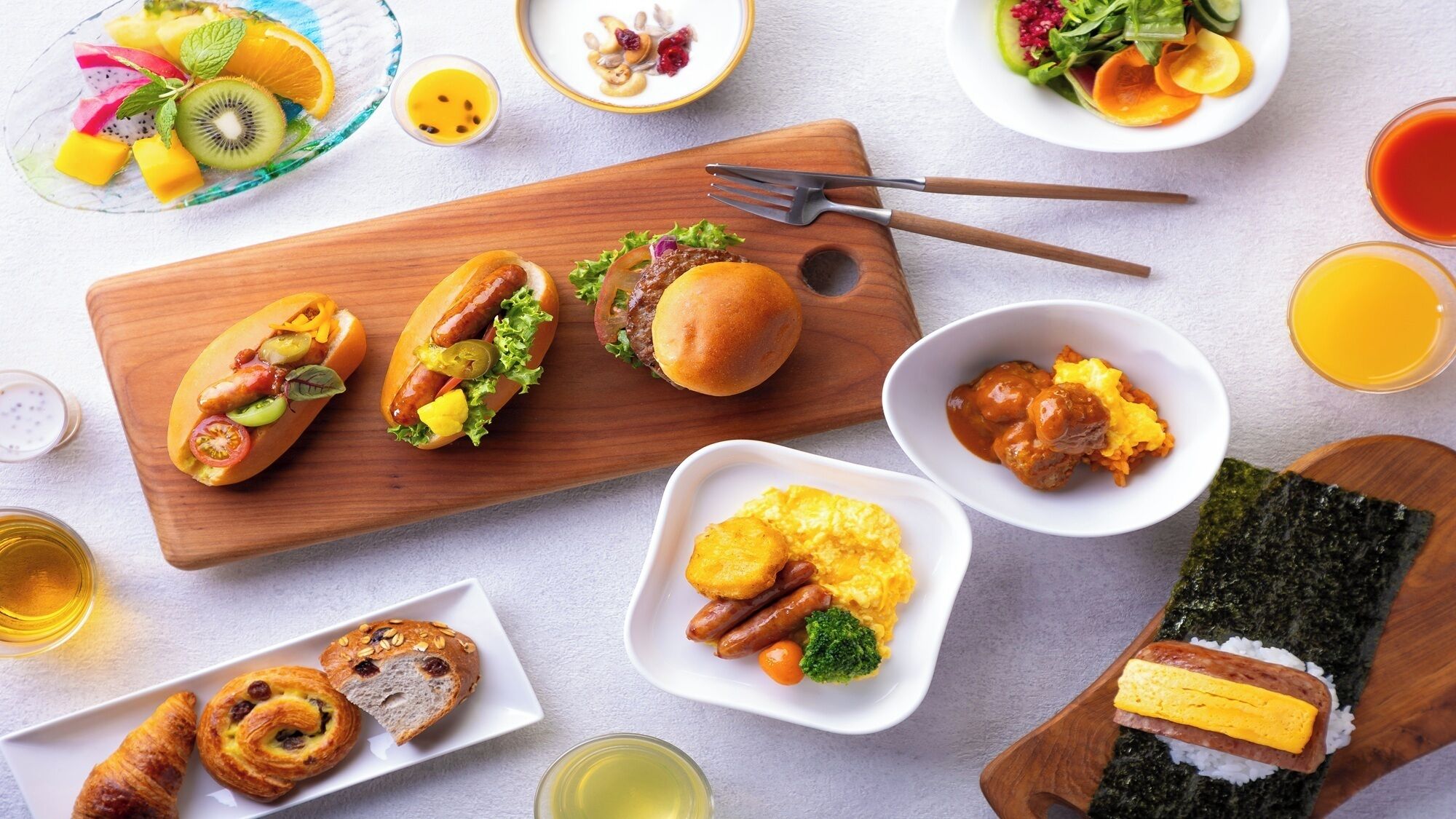 A variety of food items including hot dogs, pastries, and a plate of vegetables.