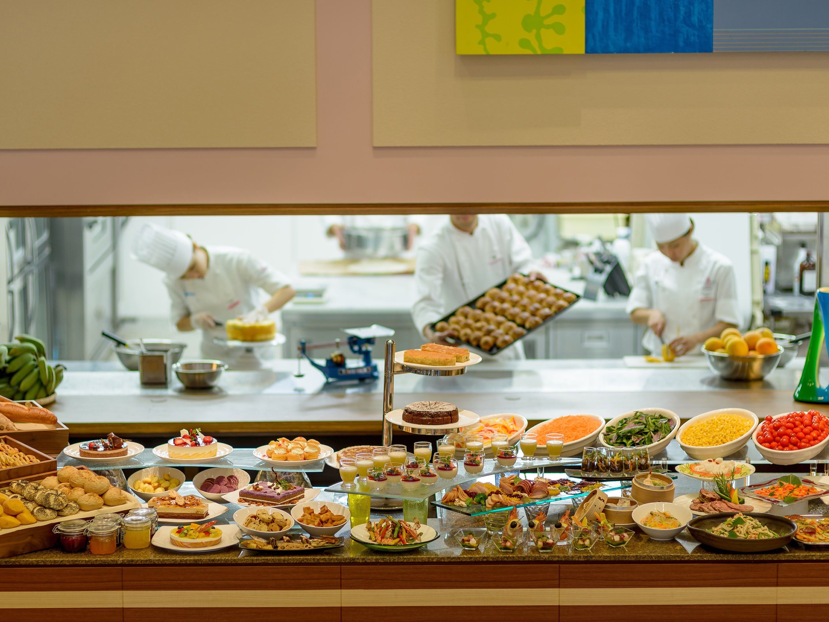 A buffet with various food items and a kitchen area in the background.