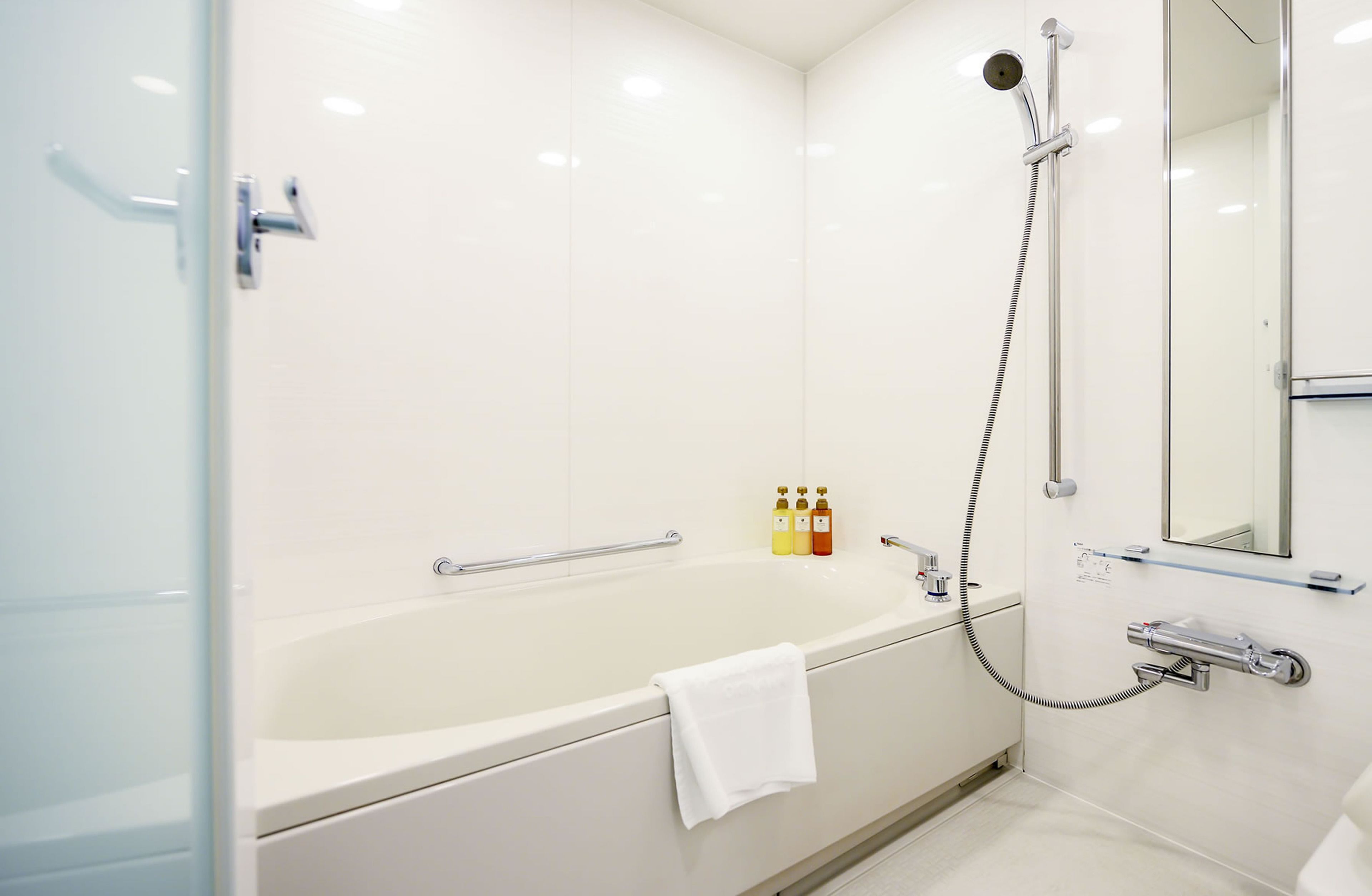 A modern bathroom with a large bathtub, a handheld showerhead, and a wall-mounted toilet.