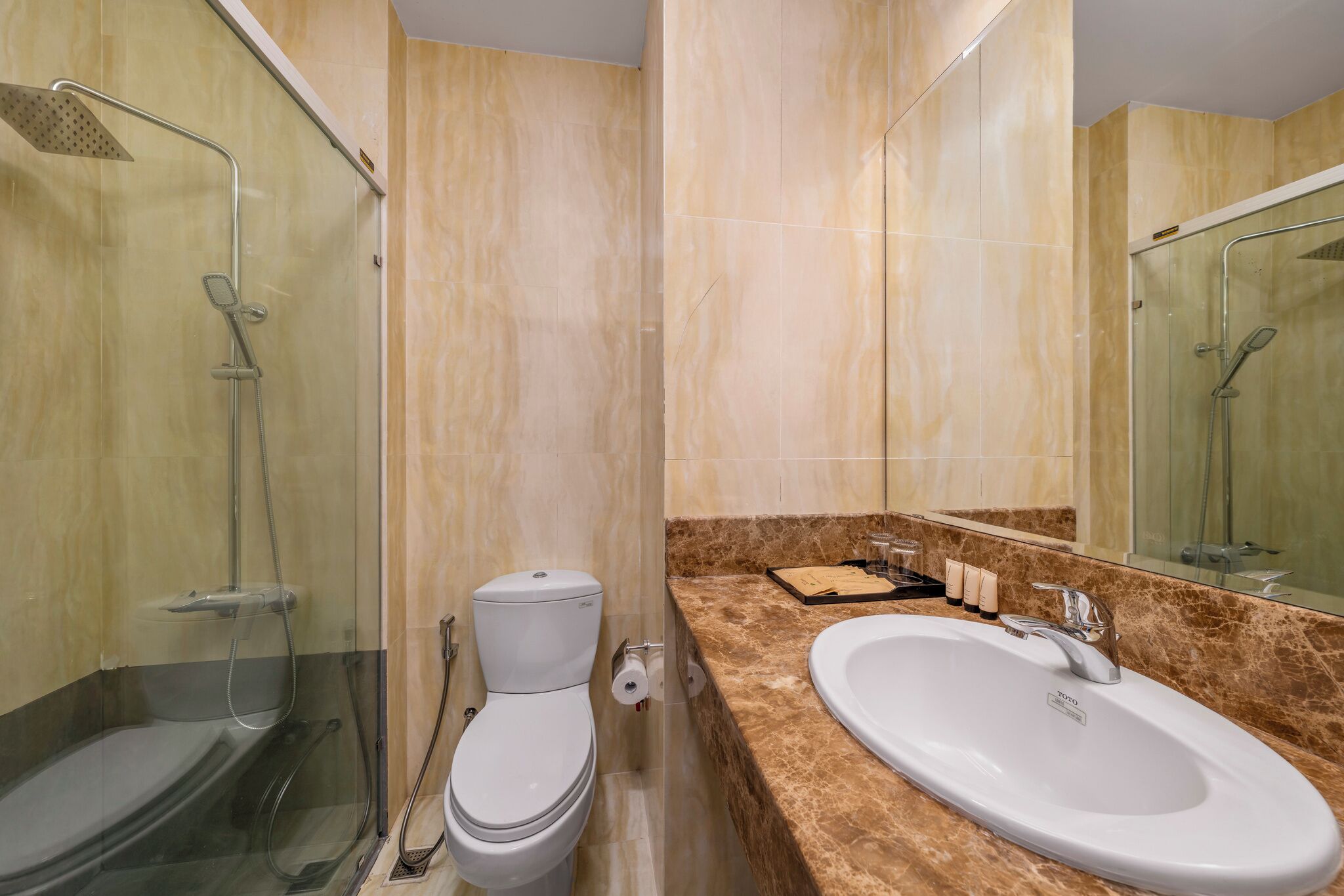 Un baño con ducha de vidrio, inodoro, lavamanos y espejo.