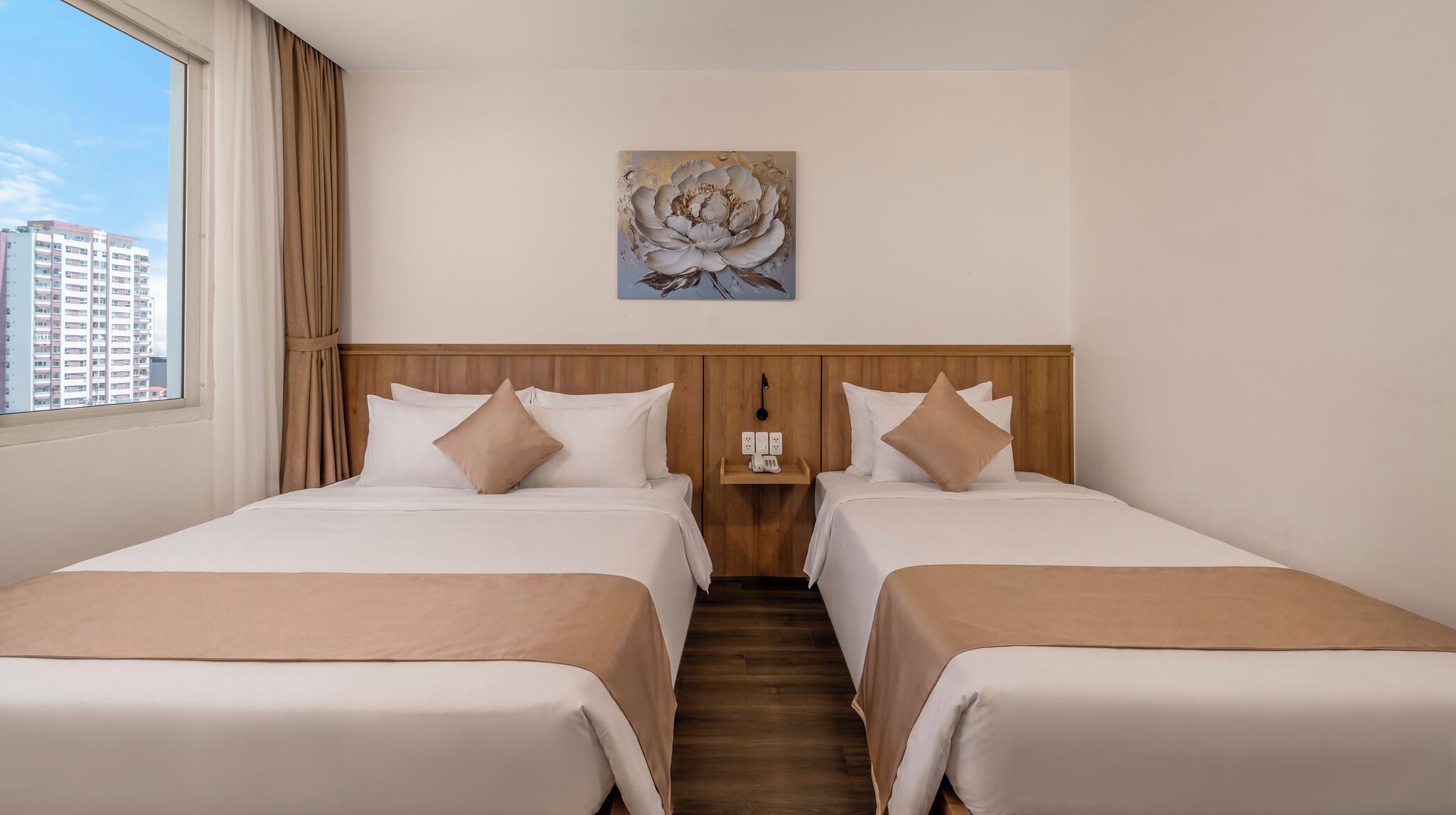 Ein Hotelzimmer mit zwei Betten, einem Holz-Kopfteil, einem Bild an der Wand und Blick auf Gebäude.