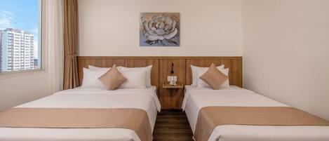 Ein Hotelzimmer mit zwei Betten, einem Holz-Kopfteil, einem Bild an der Wand und Blick auf Gebäude.