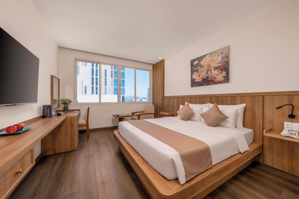 Une chambre dâhĂŽtel moderne avec un grand lit, un bureau en bois et une vue sur la ville.