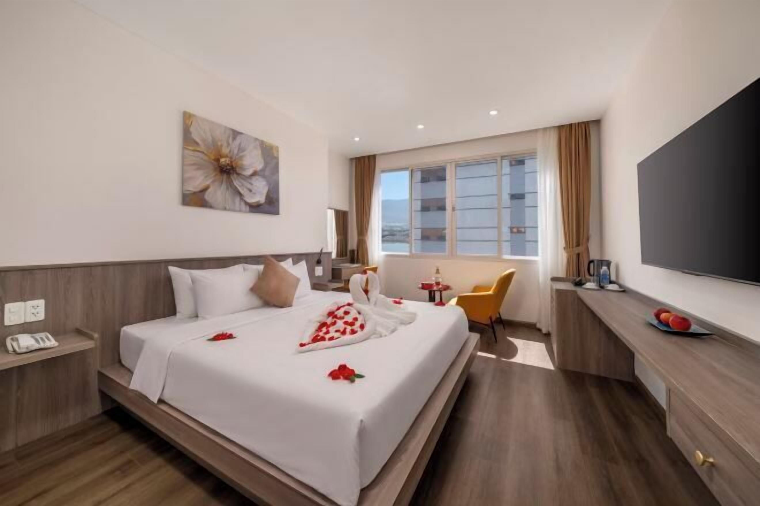 Une chambre d’hôtel comprenant un lit, une table de chevet, une chaise, un bureau, une télévision et une fenêtre.