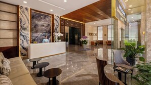 Un vestíbulo de hotel con mostrador de recepción, zona de estar y un letrero que dice 'Welcome Danang Petro Hotel'.